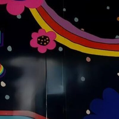 Consumerism - Photograph of mural on shopping mall wall with the text Born to Shop and fraphics of stars, flowers and circles in flouro bright colours on a black background